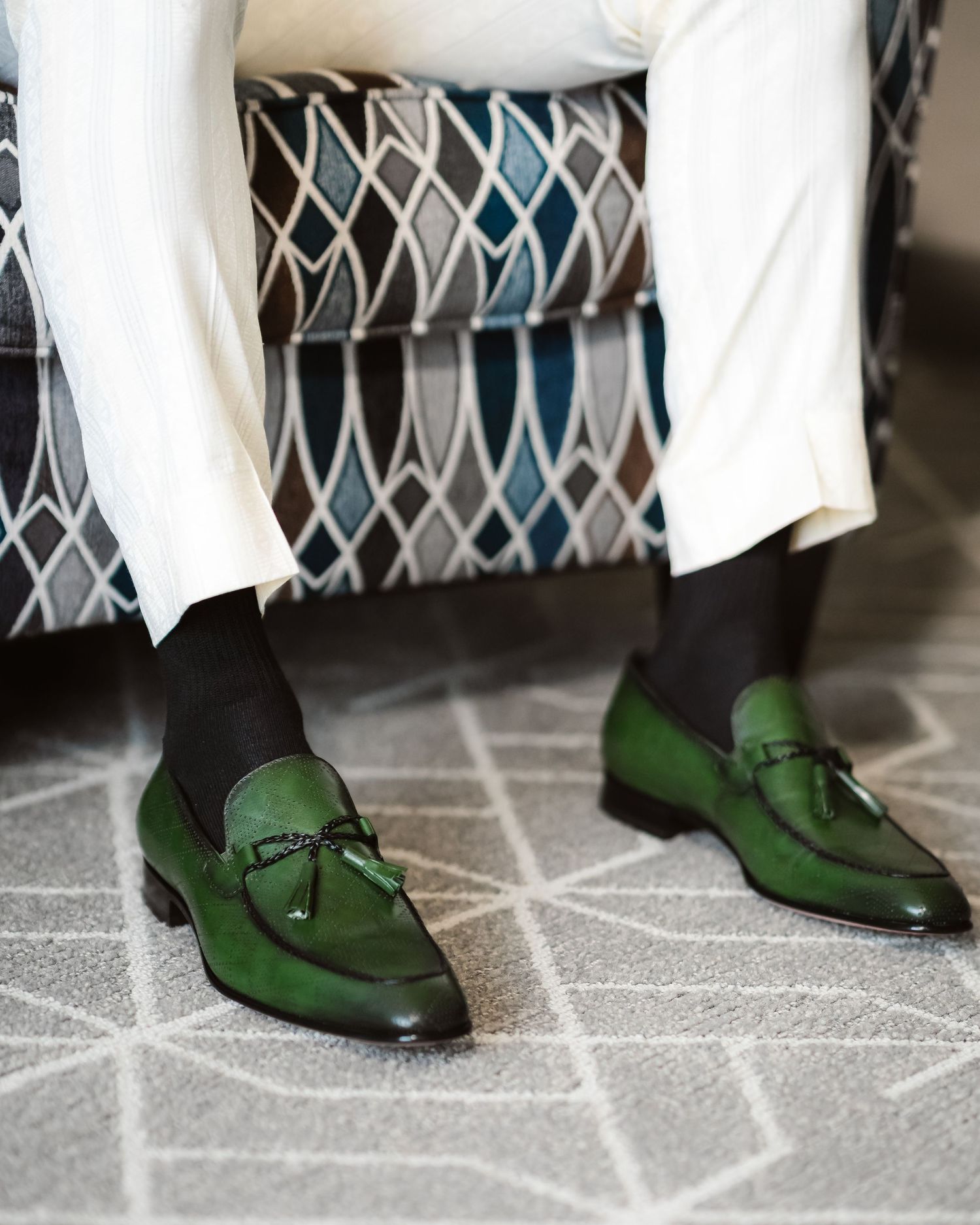 Green leather dress shoes on patterned tile floor.
