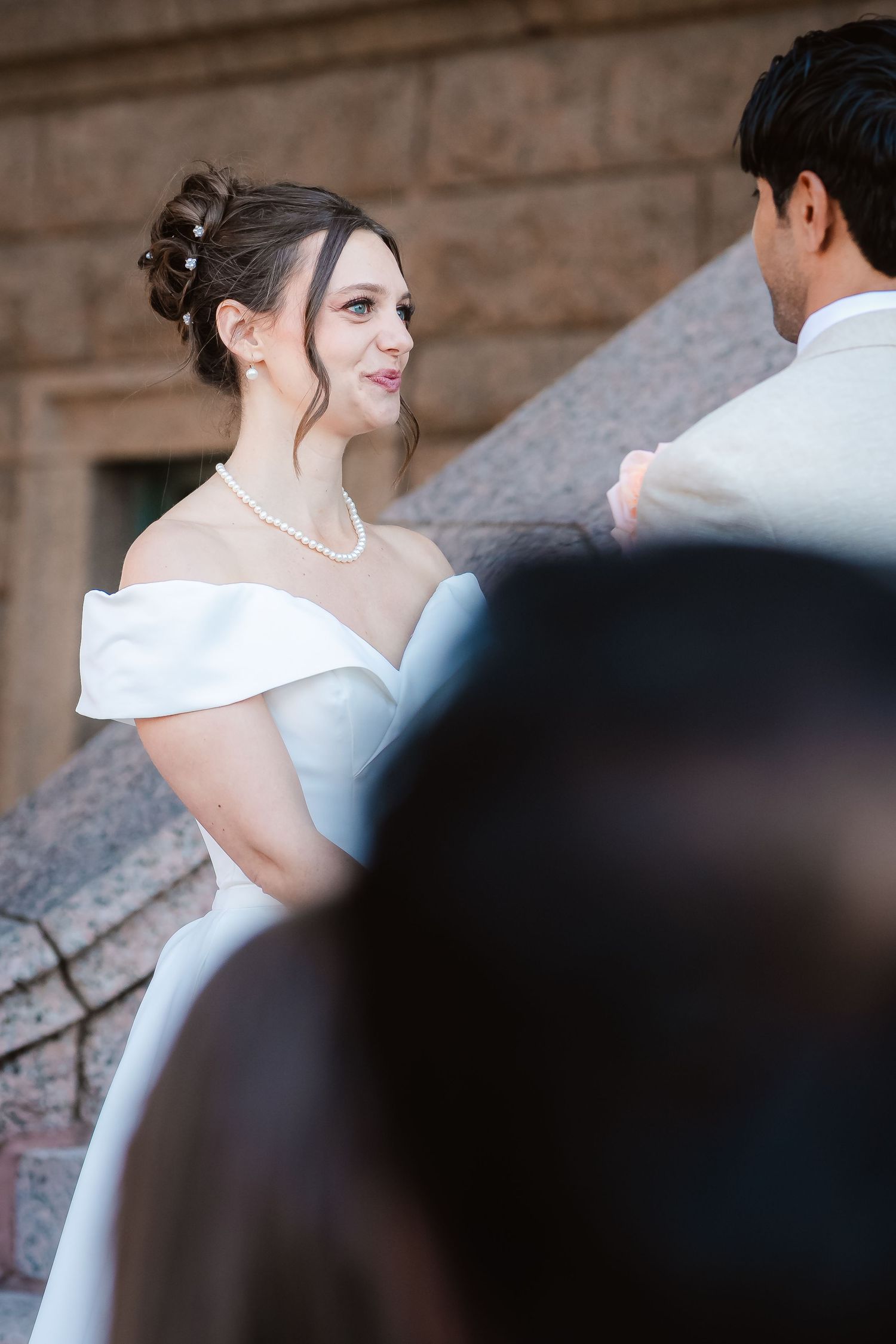 A candid moment captured during a wedding as the couple shares a loving glance near stone architecture.