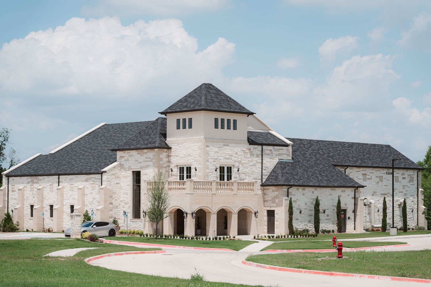 Exterior view of modern white stone wedding venue with arched entryway.