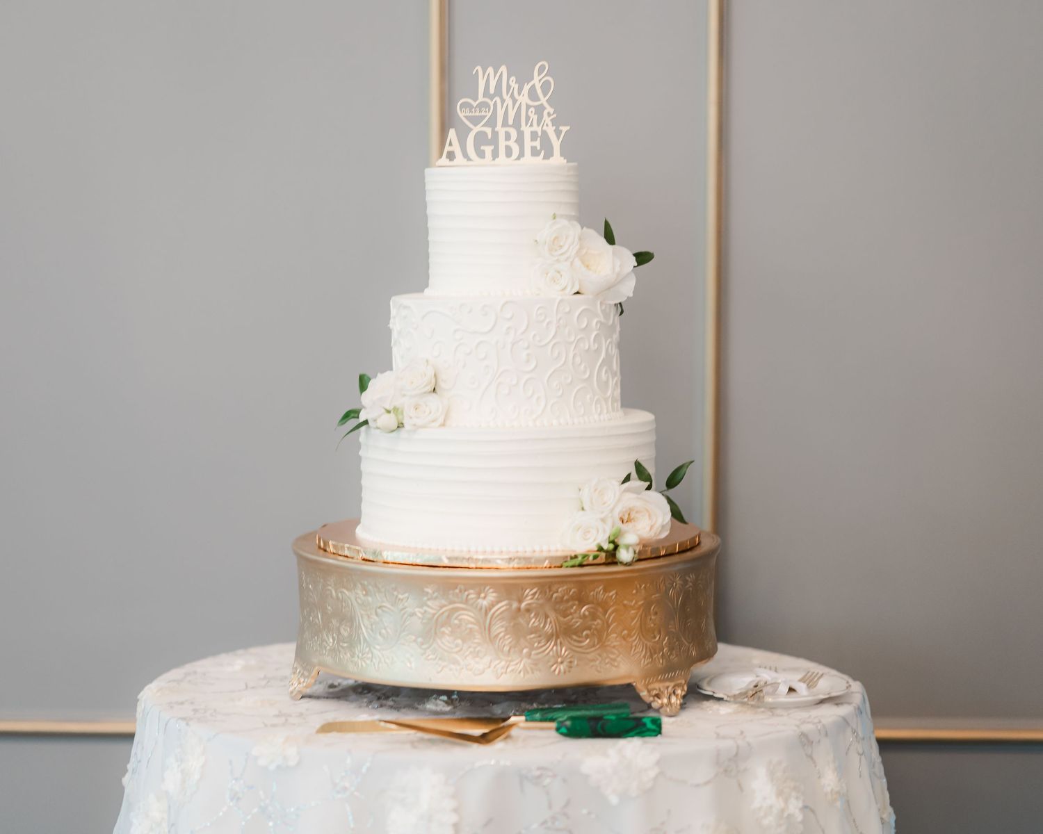 Elegant white wedding cake with gold accents and floral decorations.