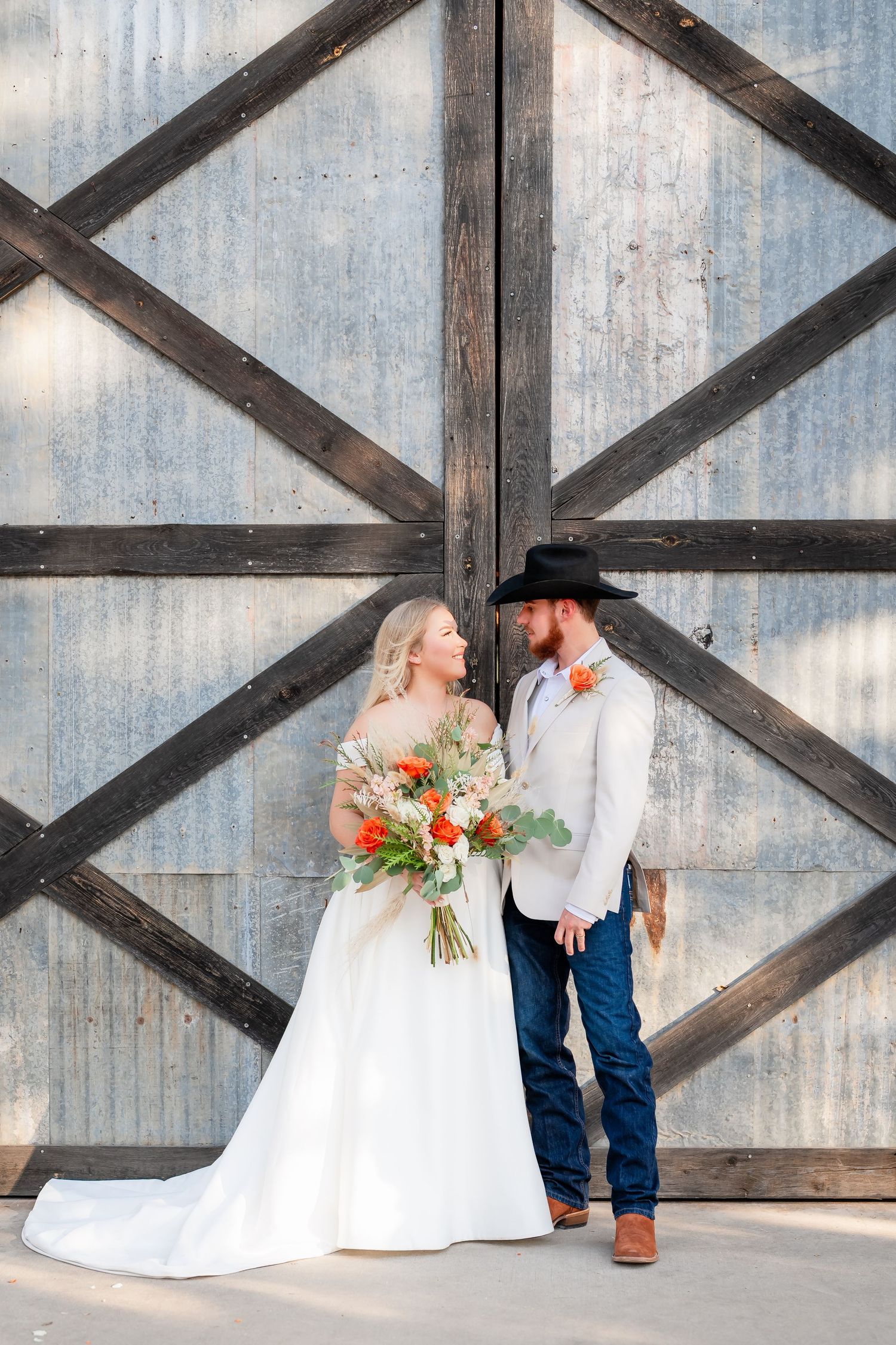 Wedding couple poses against industrial metal and wood backdrop.