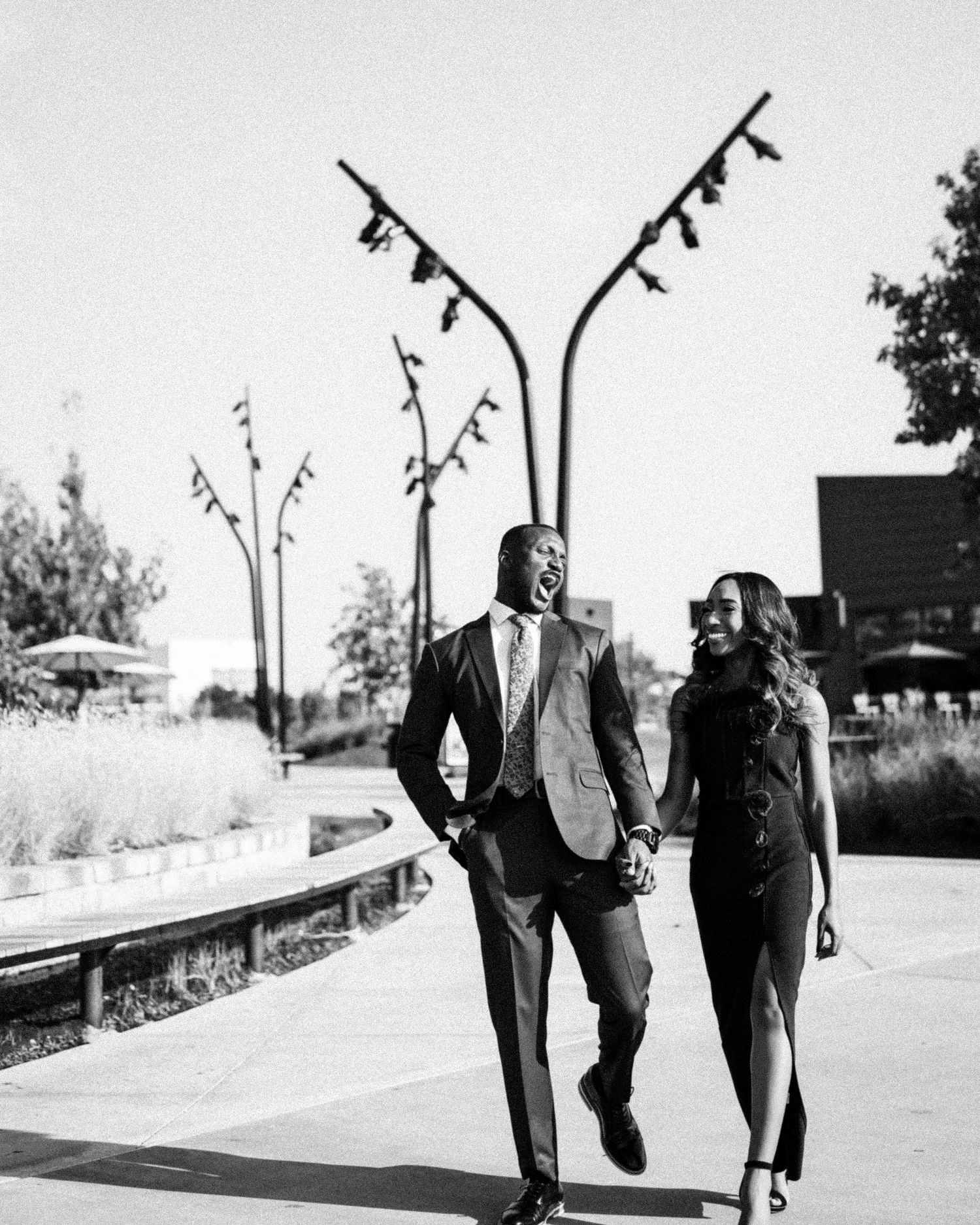 Black and white photo of couple walking together in formal wear outdoors.