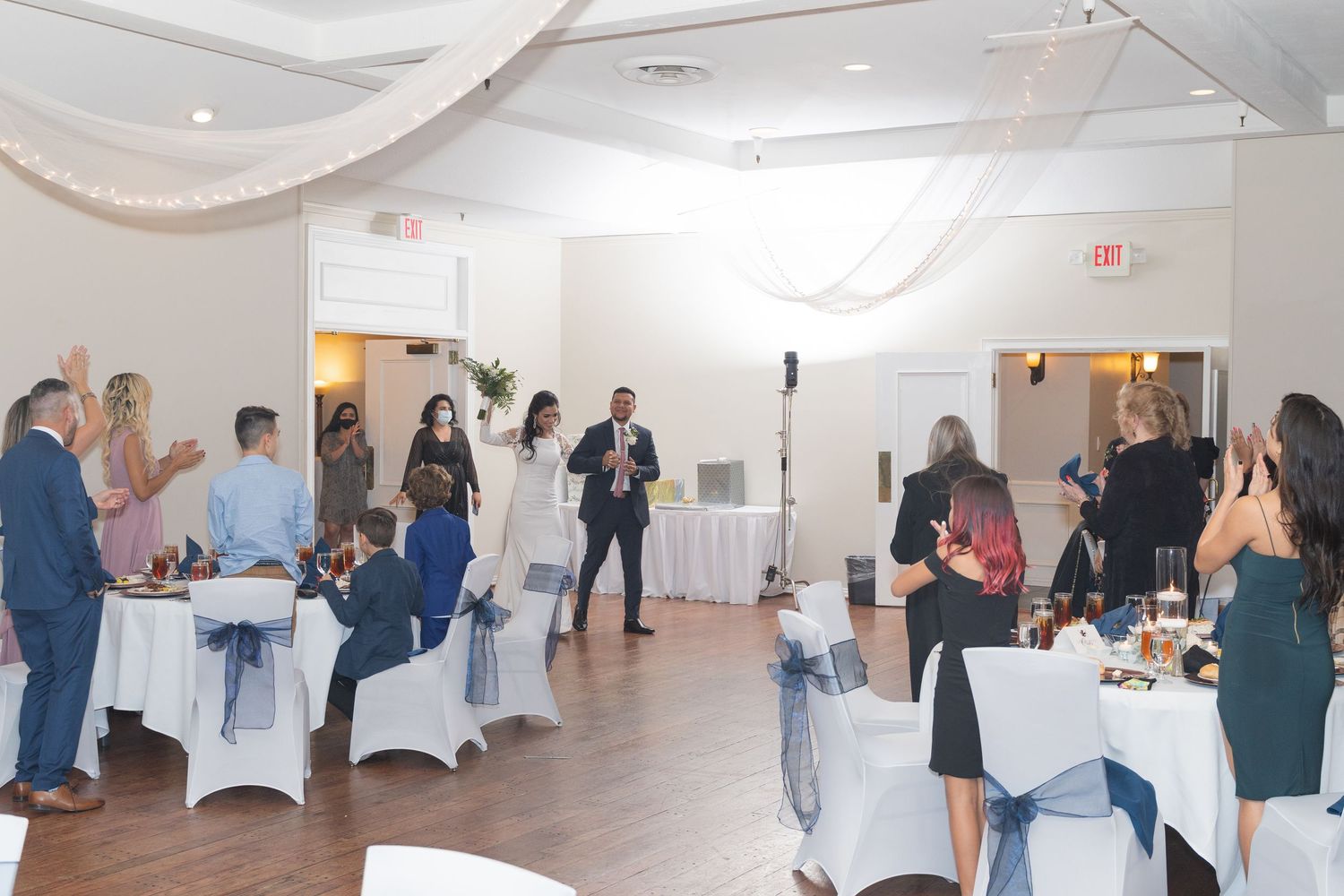 Spacious wedding reception hall with white chairs and elegant table settings ready for guests.