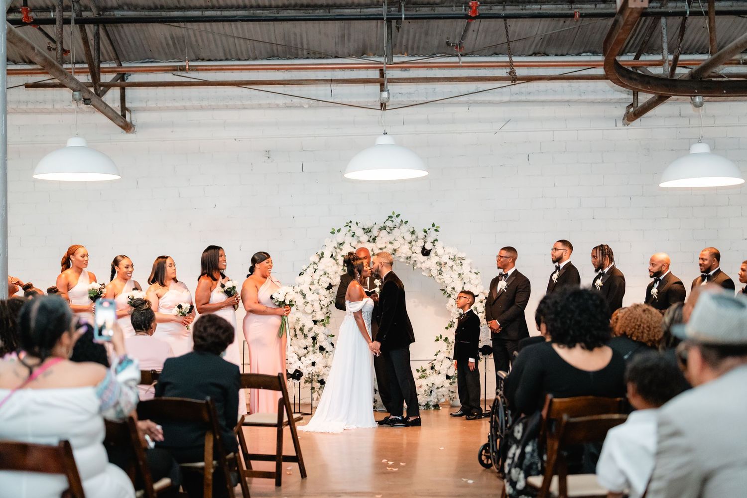 An elegant indoor wedding ceremony setup with guests seated in rows at a modern industrial venue.