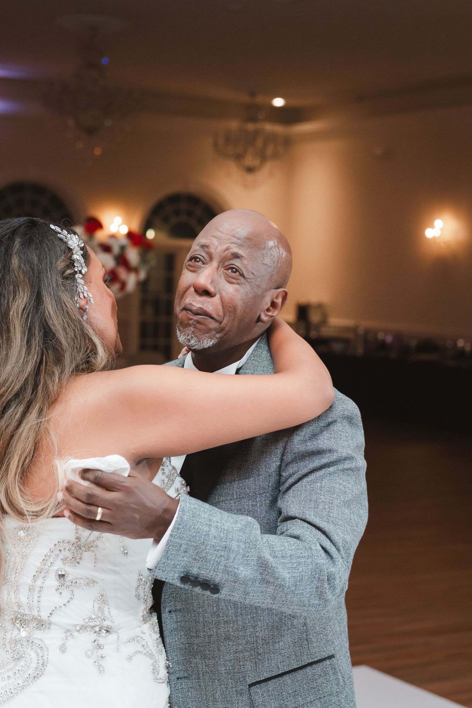 A couple shares an intimate dance moment at their wedding reception in a warmly lit ballroom.