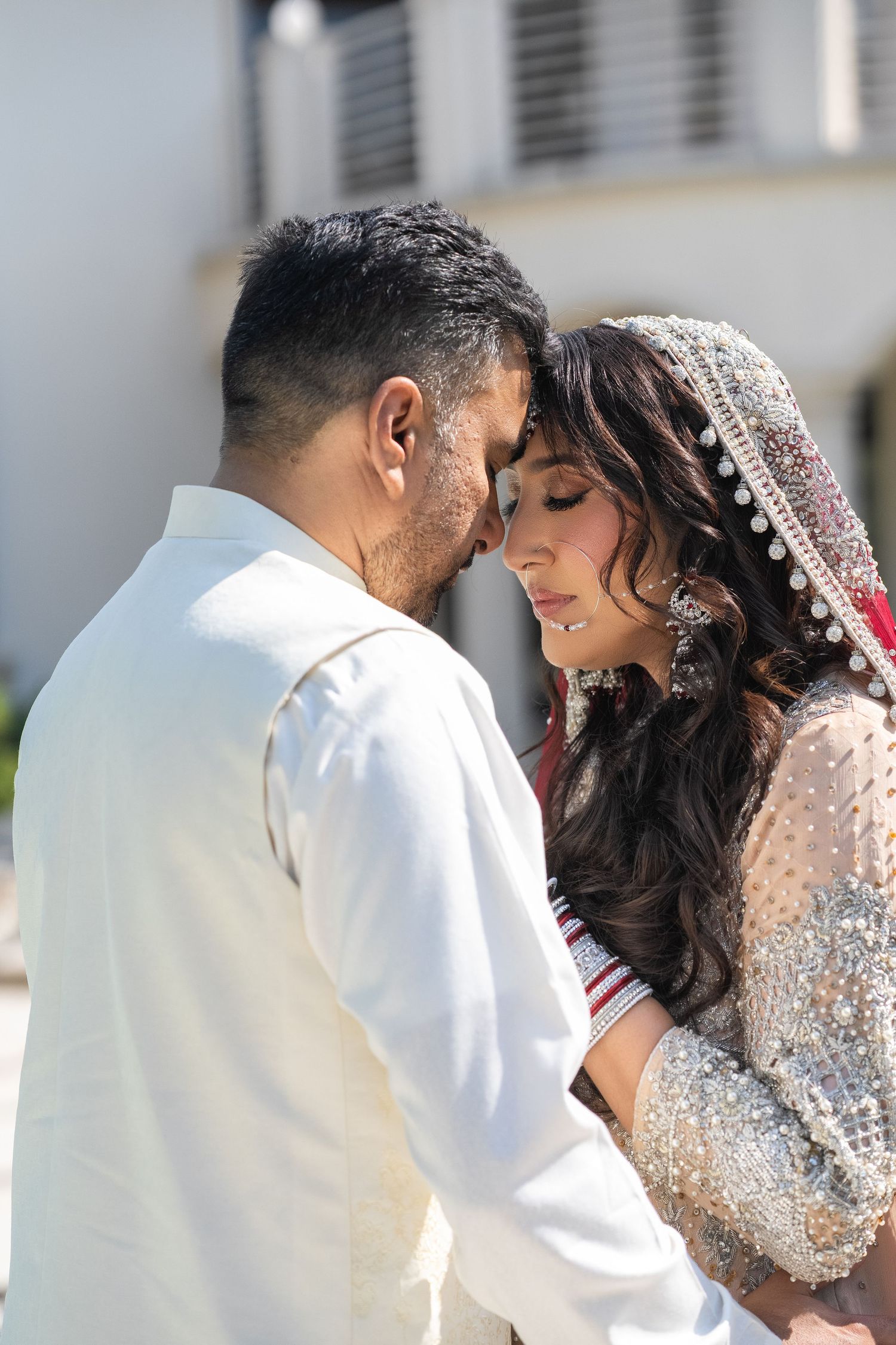 An intimate wedding portrait showing a tender moment between newlyweds in traditional attire.