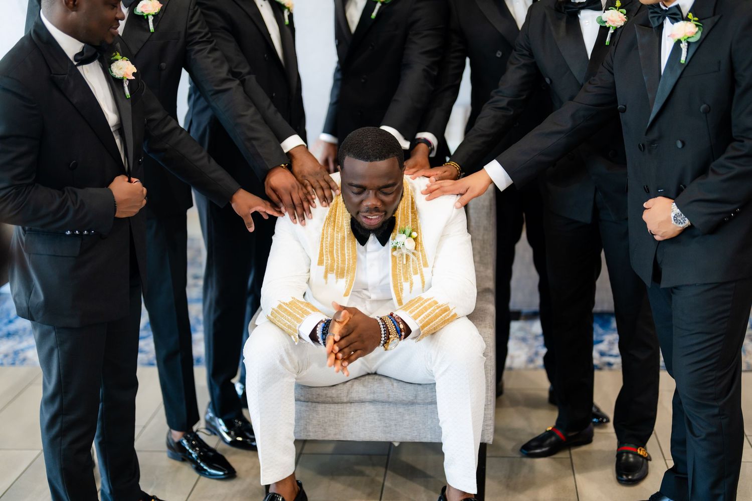 Group of groomsmen in black tuxedos and bow ties lined up at a formal event.