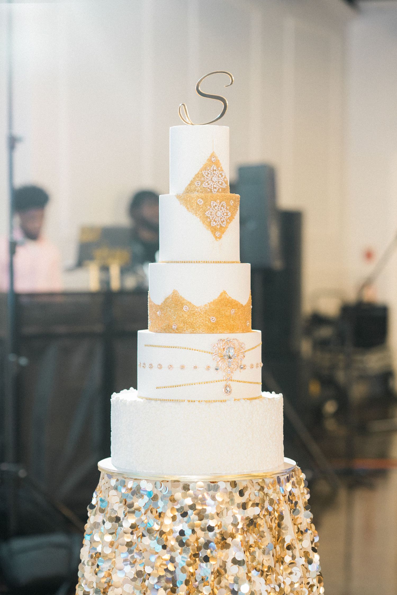 Stunning white and gold wedding cake decorated with metallic accents and crystal embellishments.