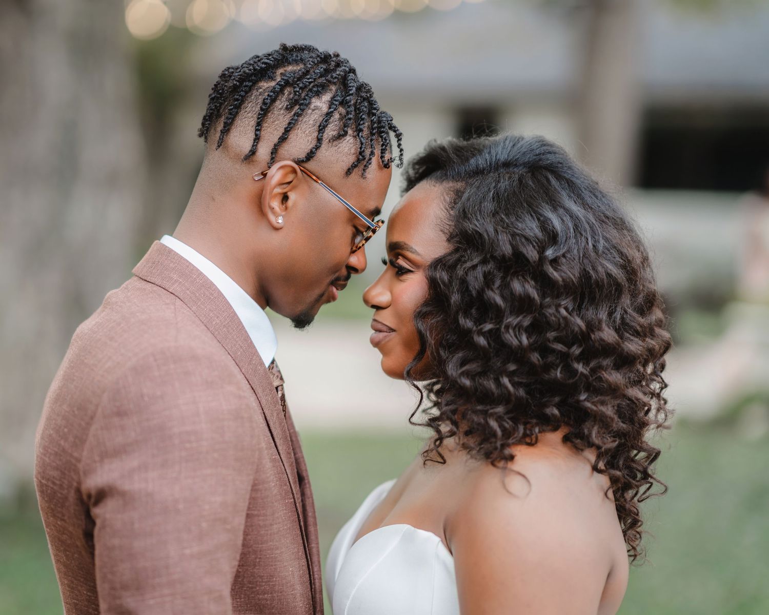 Romantic wedding couple shares an intimate moment outdoors with bokeh lights in the background.