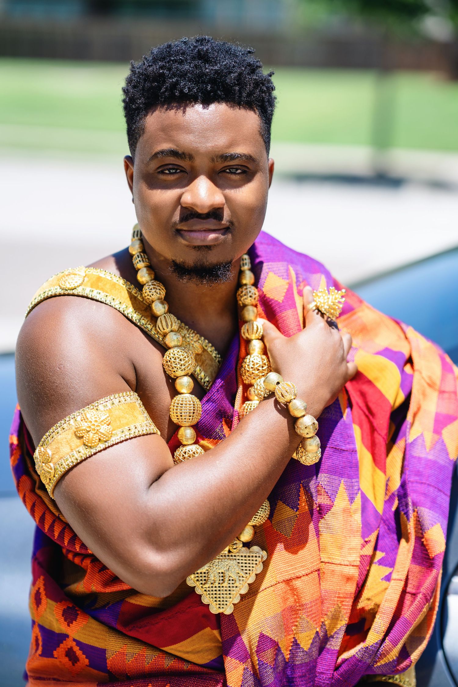 Vibrant traditional attire featuring ornate gold jewelry and colorful patterned fabric in orange and purple tones.