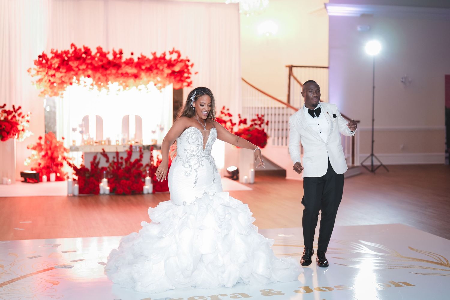 Wedding reception dance floor scene with red floral decorations and white decor elements.