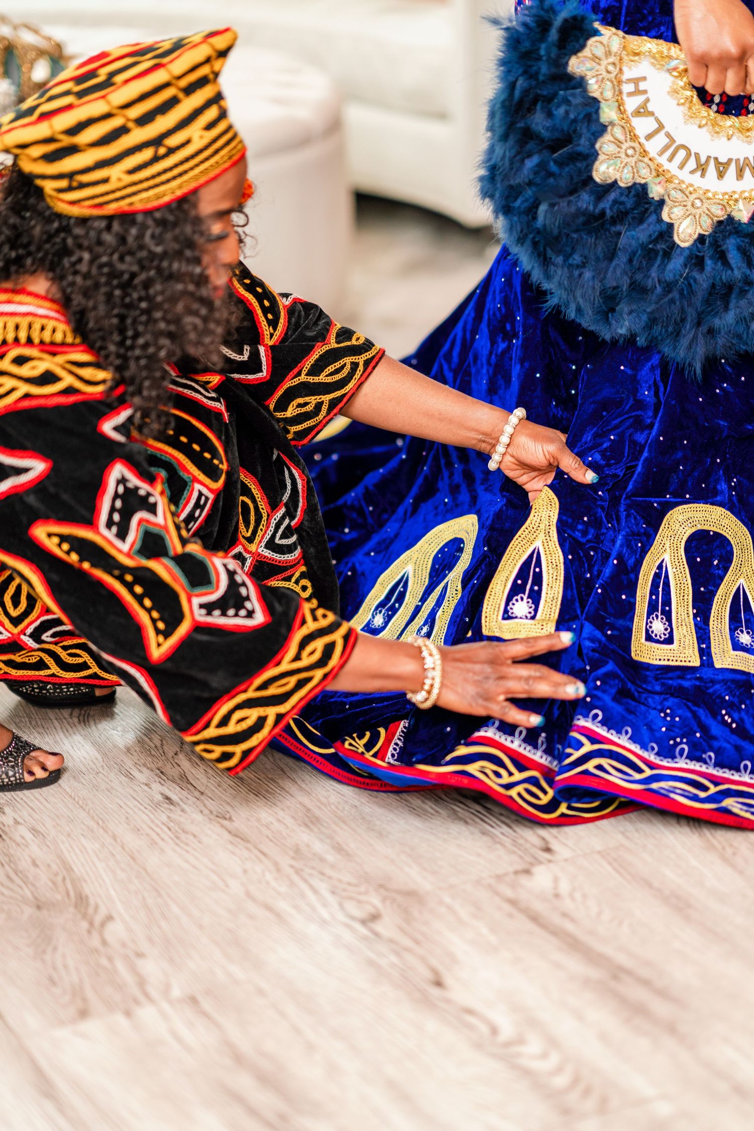 Detailed view of ornate blue and gold traditional ceremonial dress with intricate embroidery on white floor.