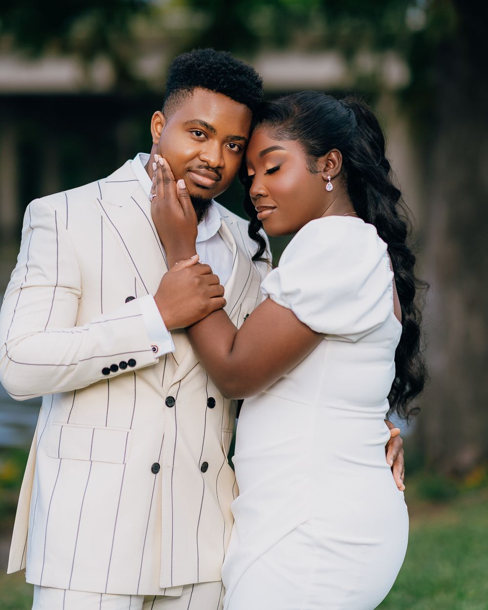A romantic couple shares tender moments in coordinated white and cream outfits during an outdoor photoshoot.