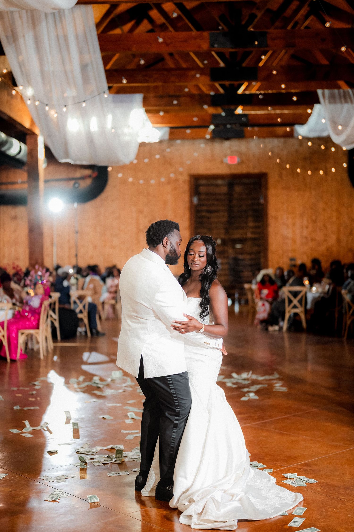 Wedding reception dance floor with guests celebrating in a rustic brick venue with string lights.