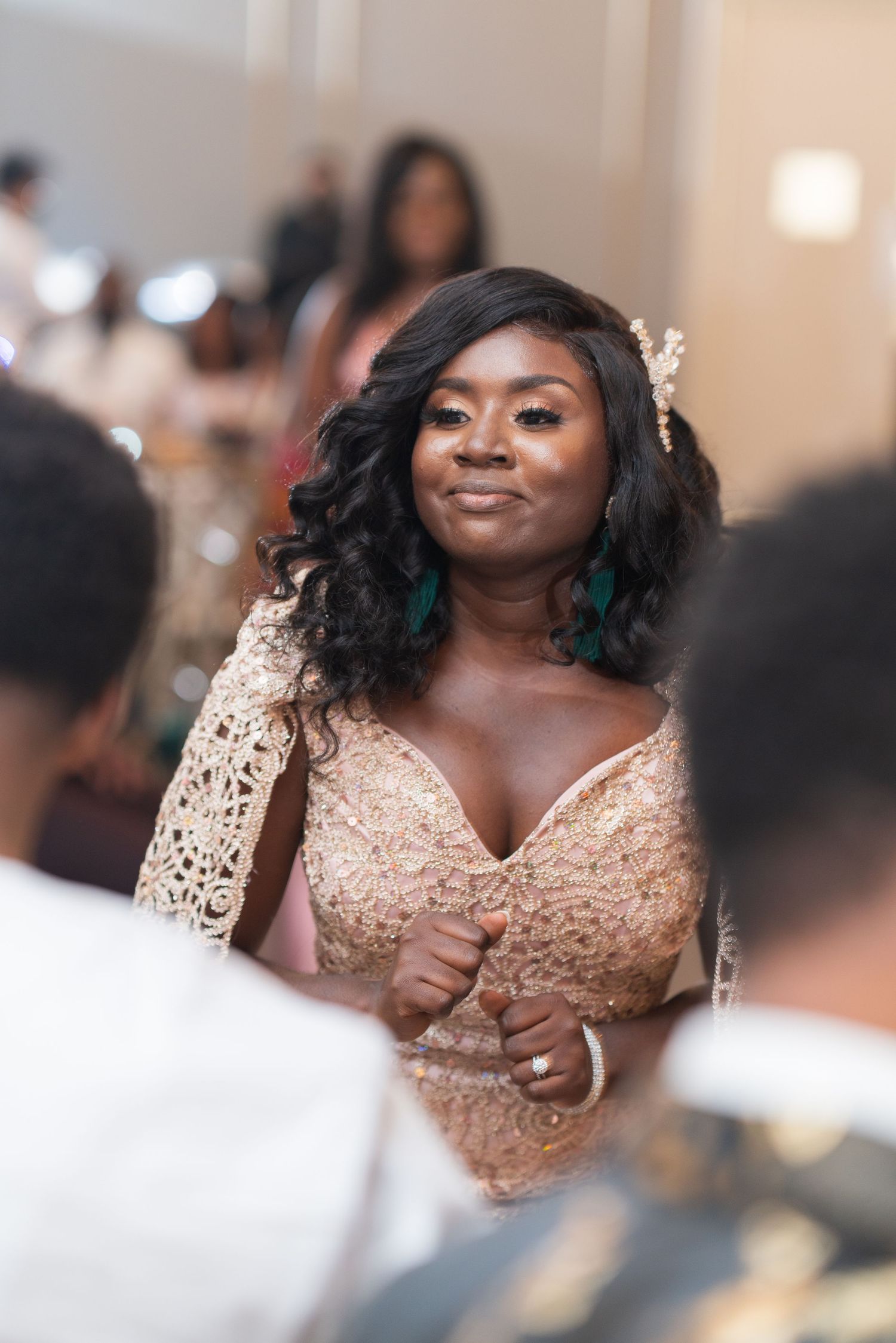 A person in a blush lace dress smiles during a wedding celebration.