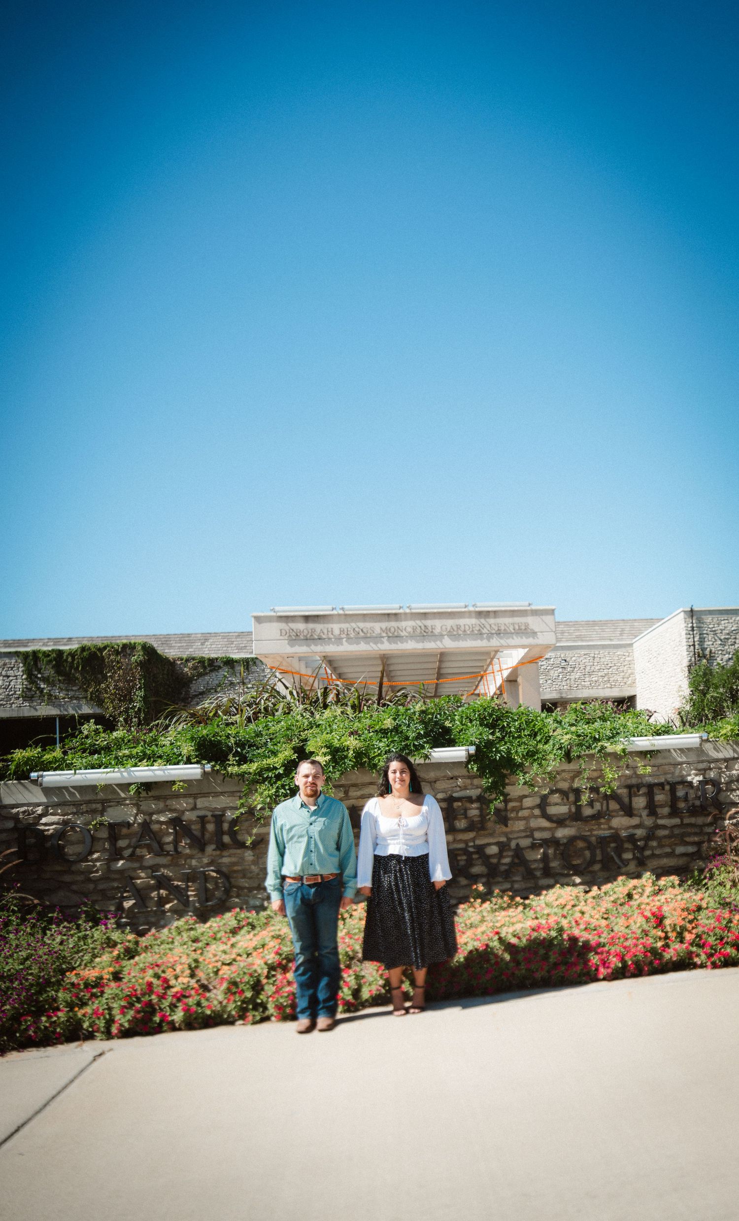 Stone wall garden backdrop with colorful flowers blooming along the base on a clear blue sky day.