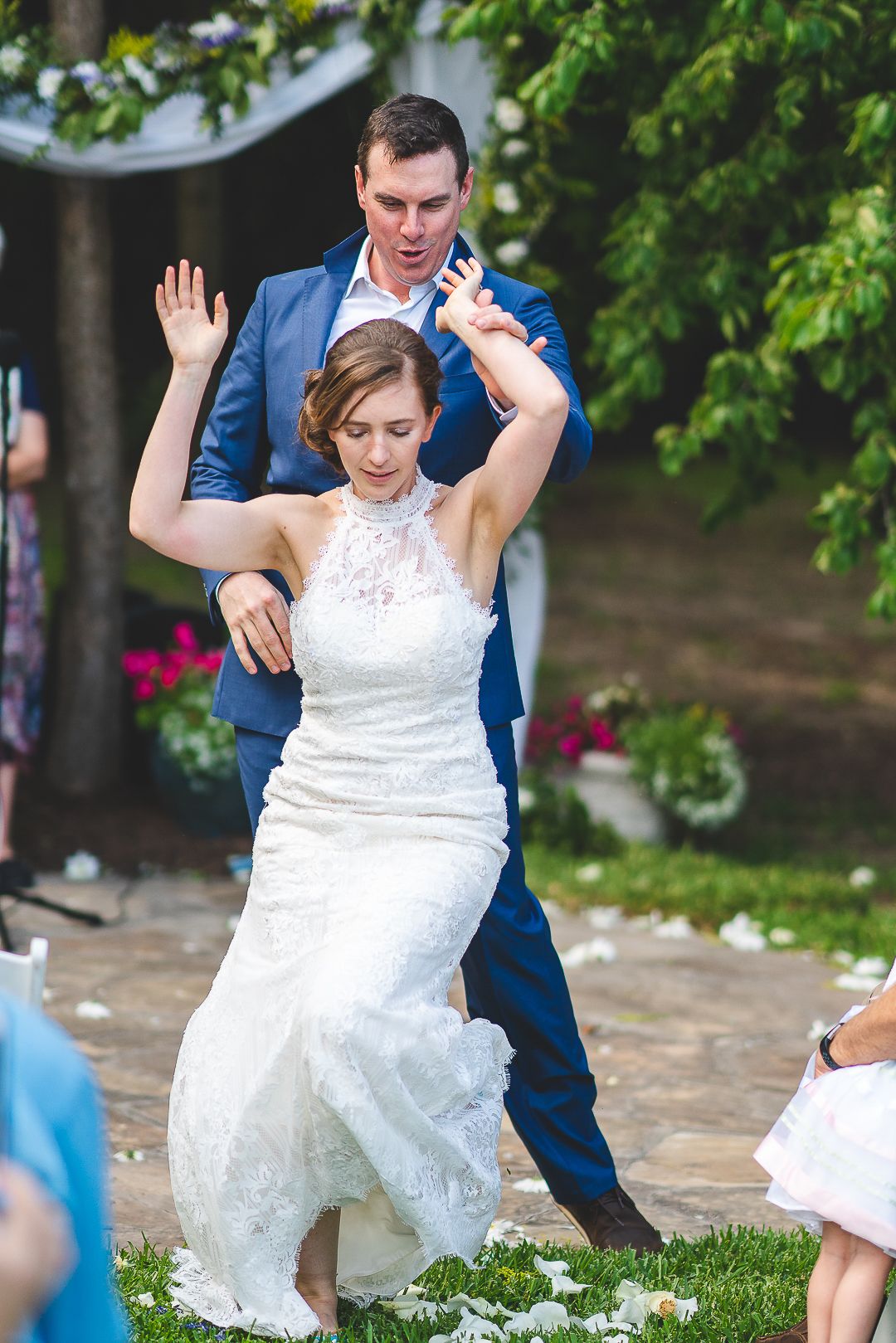 A playful moment during a wedding reception on outdoor garden grounds.