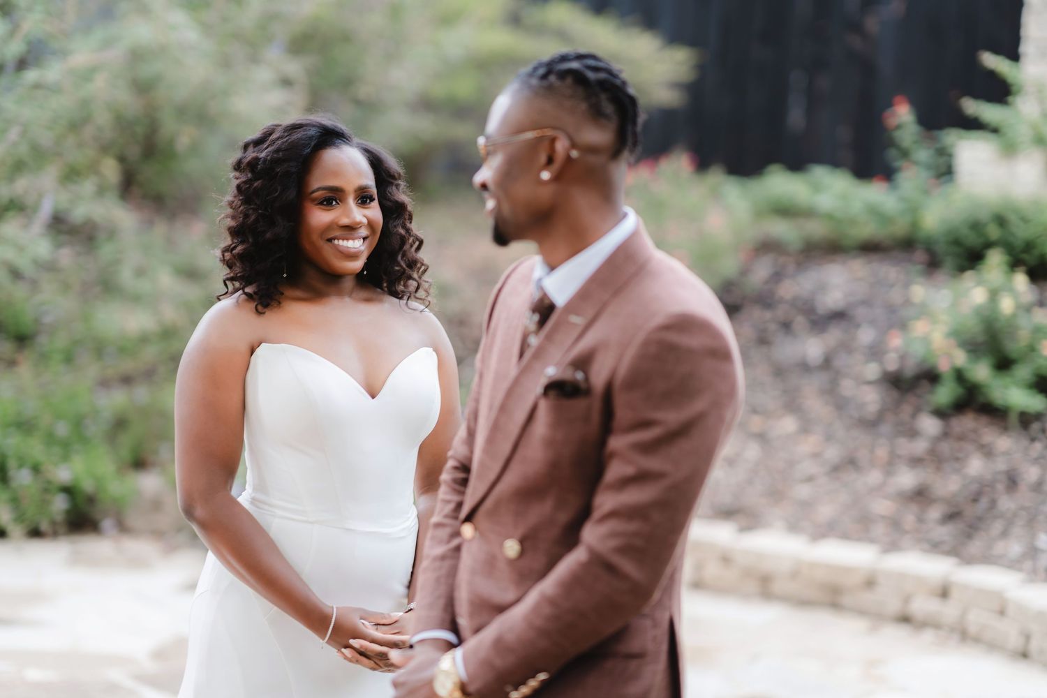 Candid outdoor wedding photography session with natural greenery in the background.