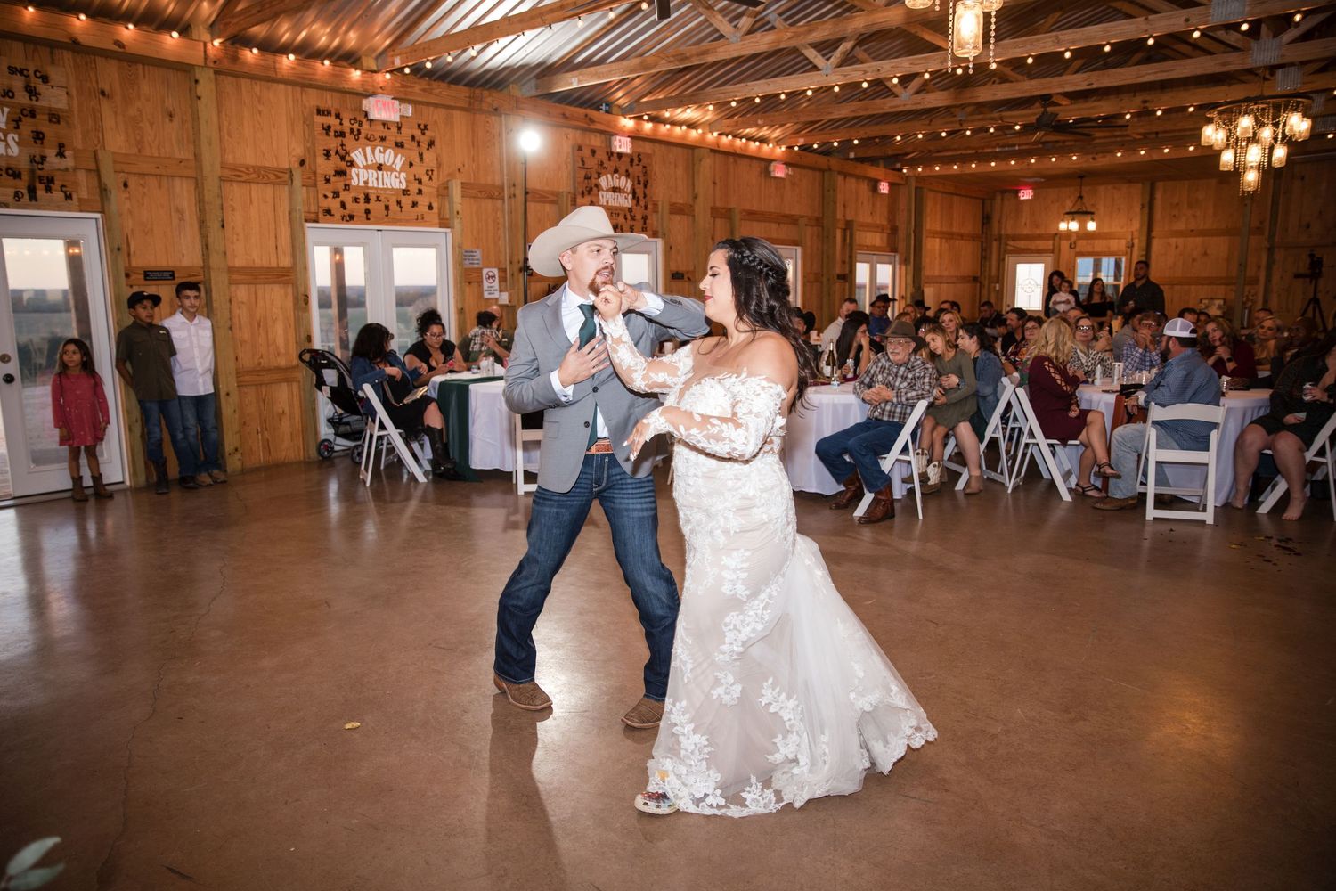 Couples dance together under warm lighting at a rustic barn wedding reception.