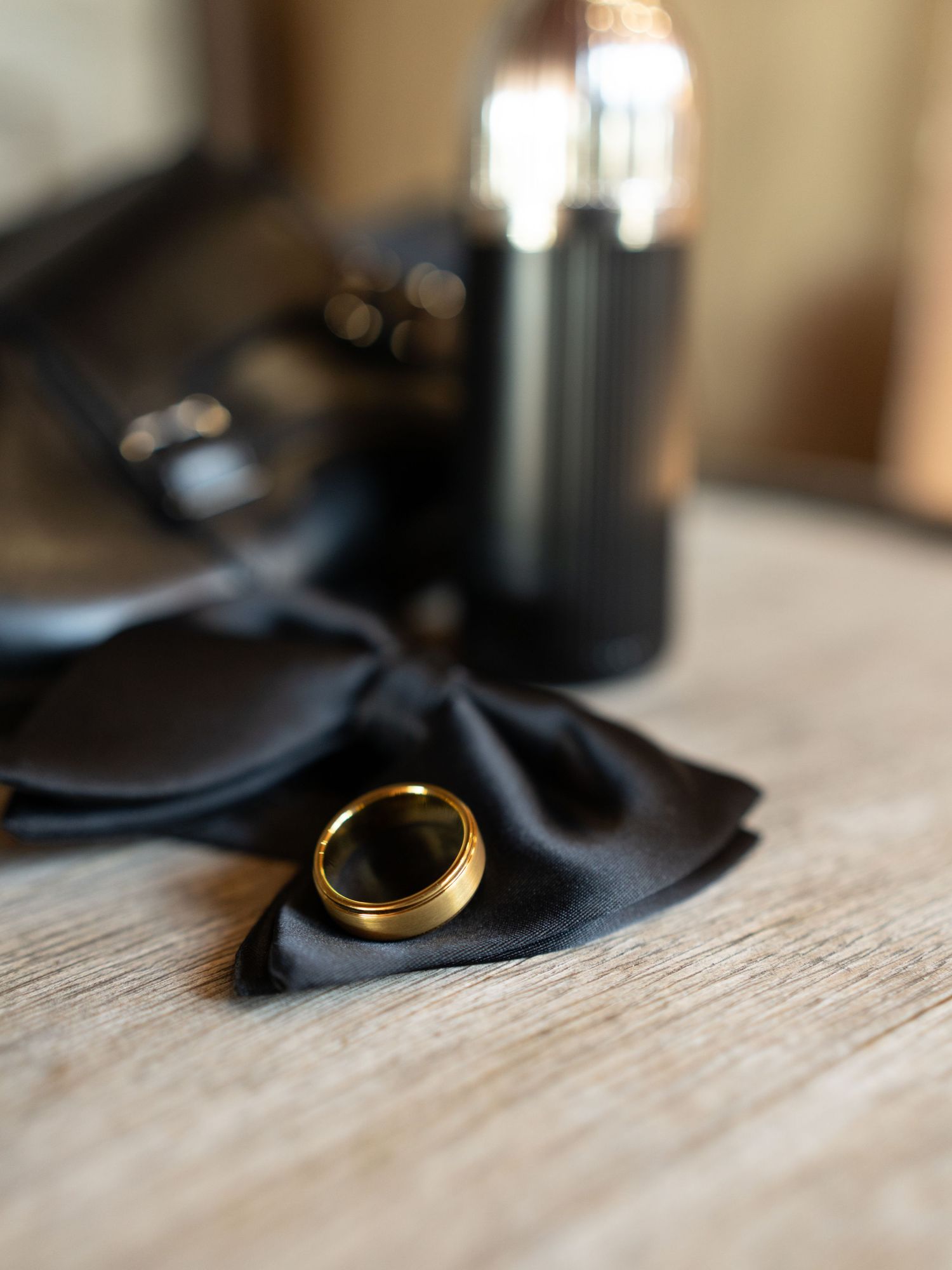 Close-up view of a gold wedding ring resting on black fabric with shallow depth of field.