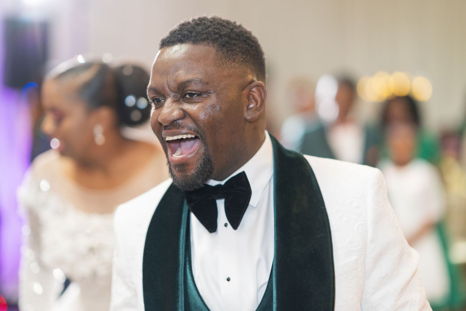 Joyful wedding celebration moment captured in white tuxedo and black bow tie.