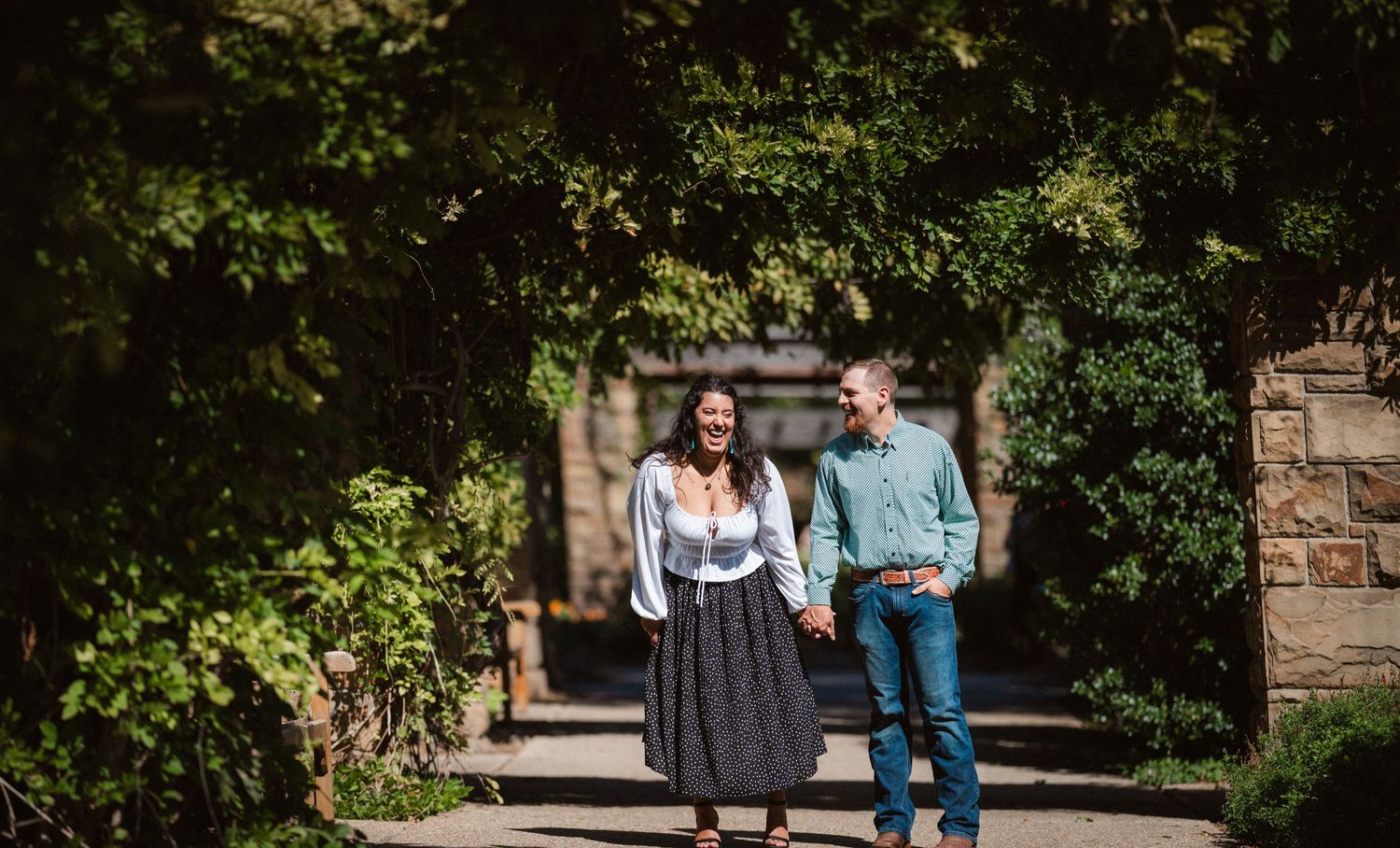 A couple walking along a peaceful garden pathway surrounded by lush greenery.