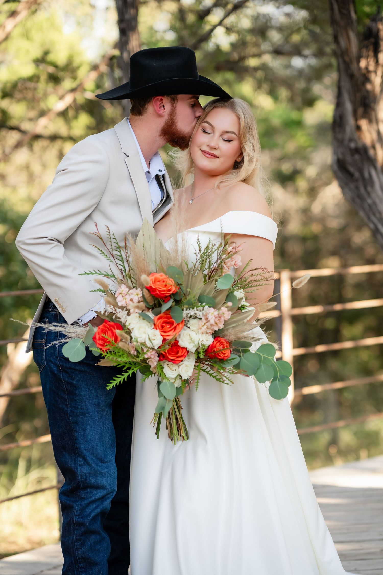 Wedding couple sharing intimate moment with colorful bouquet on outdoor deck.