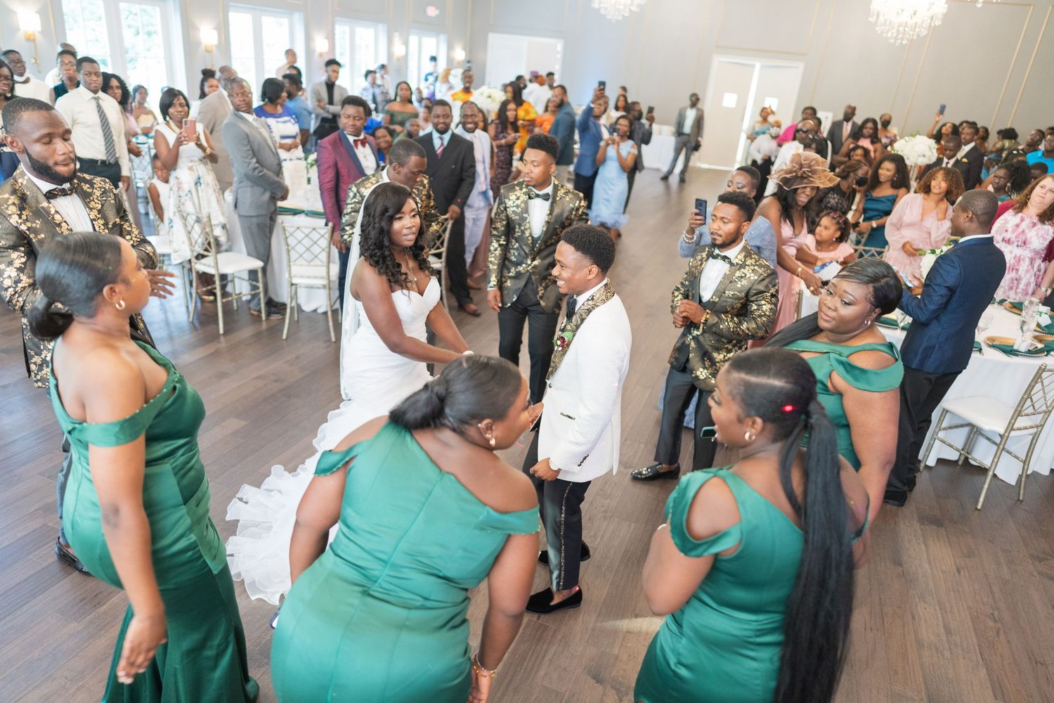 Wedding reception venue with guests in emerald green attire mingling and celebrating.