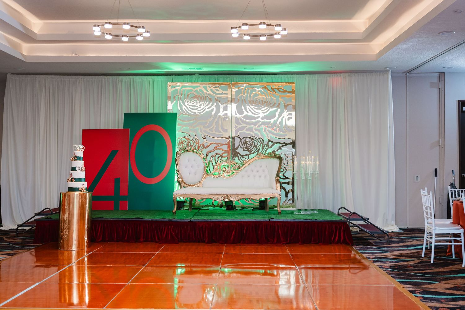 Event stage setup with large red and green 40 numbers against white drapes and green accent lighting.