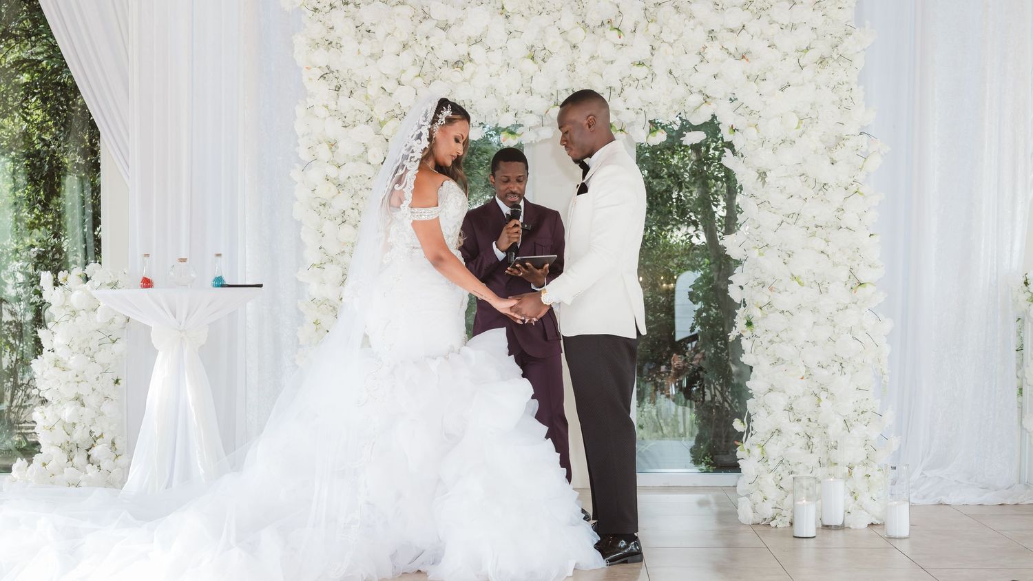 Wedding reception photos with elegant white flower wall decorations and flowing drapery.