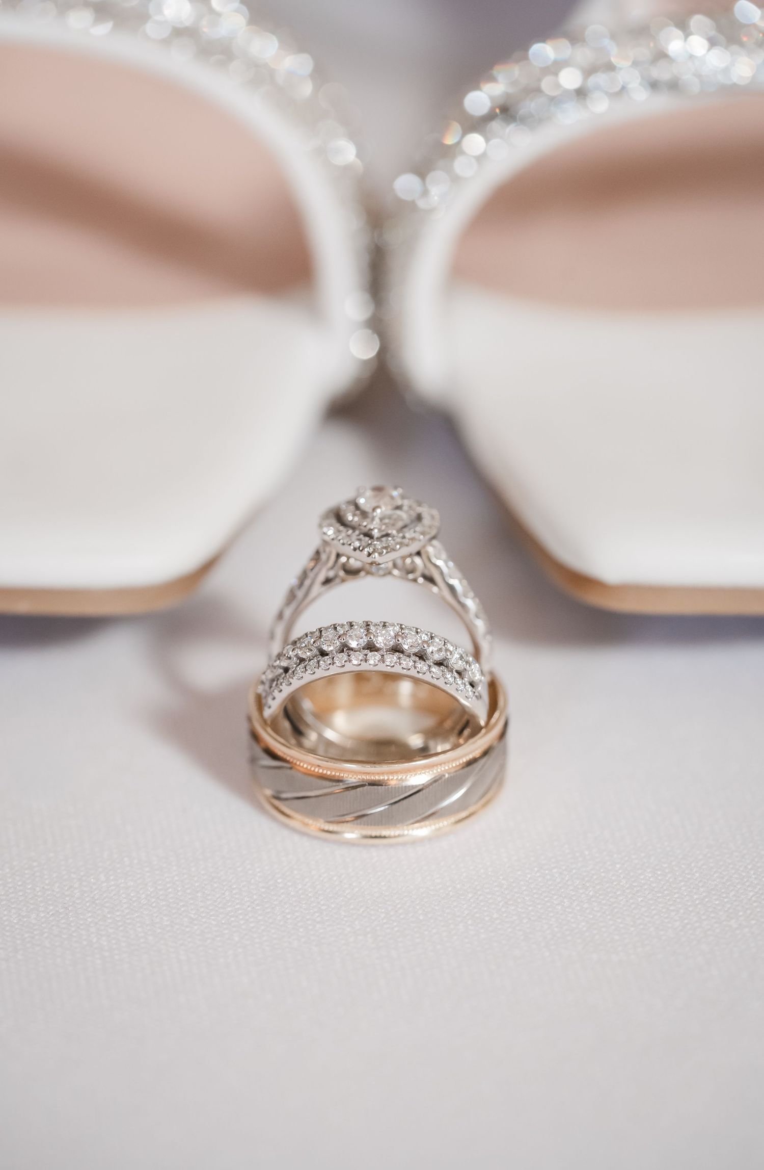 Close-up view of elegant wedding rings with diamonds and intricate details against a soft blurred background.
