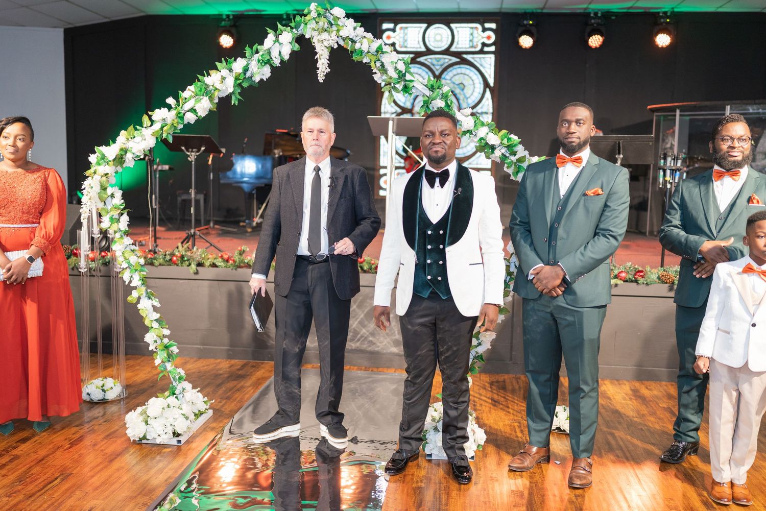 Wedding reception venue decorated with green floral arches and warm lighting for evening celebration.