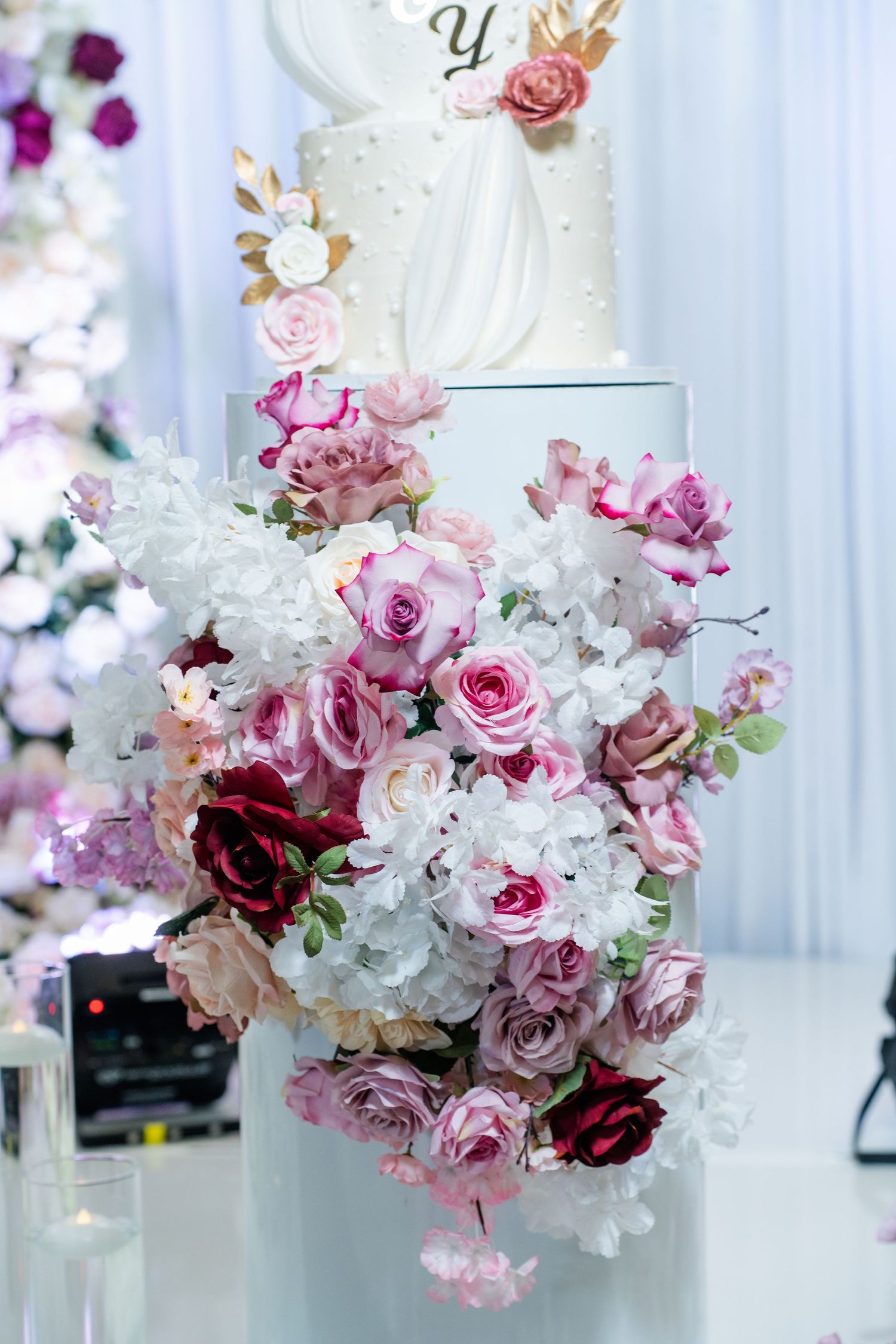 Luxurious floral arrangement featuring pink and white roses with elegant crystal chandeliers in background.