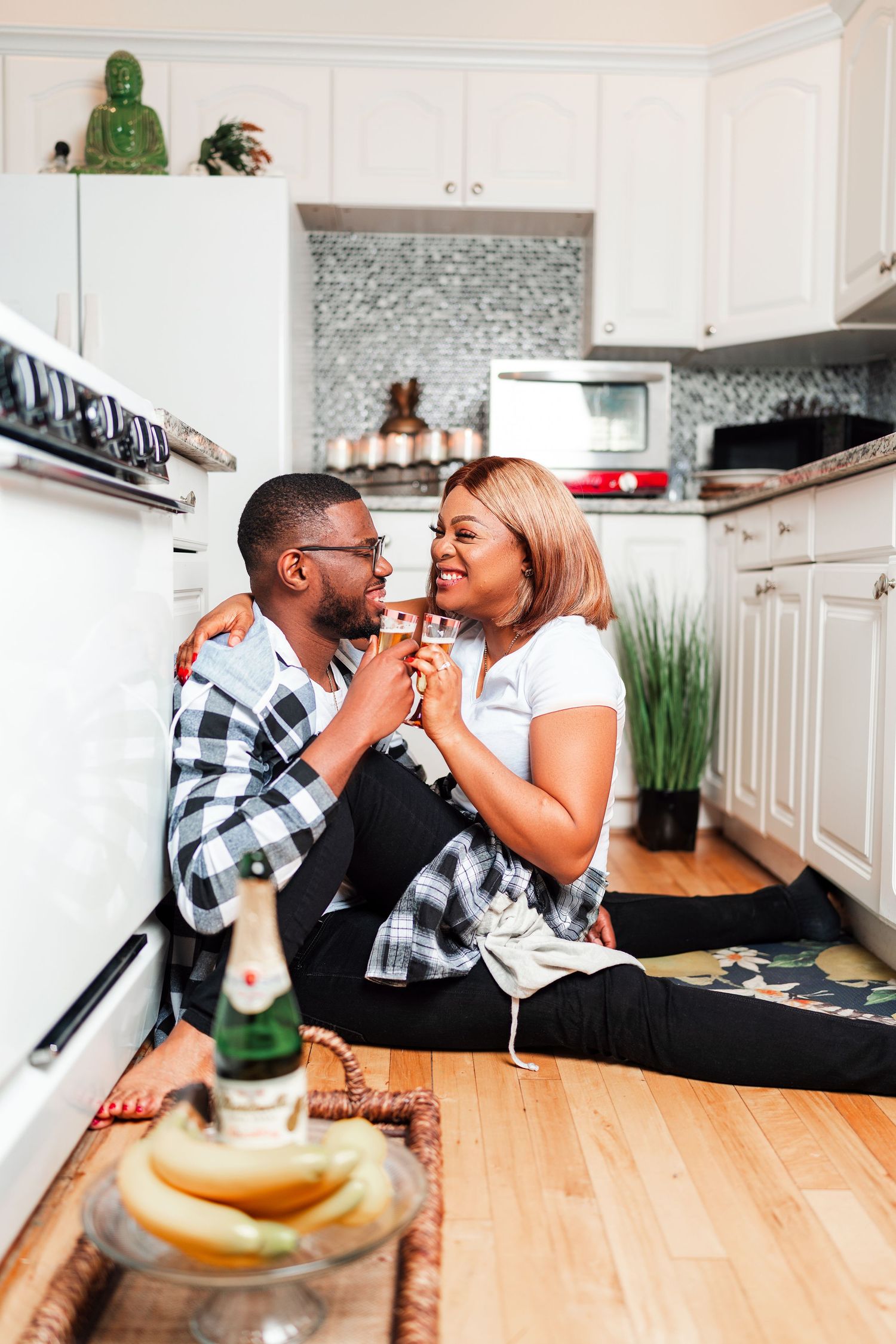 A couple shares playful moments while sitting at a wooden kitchen counter with pancakes.
