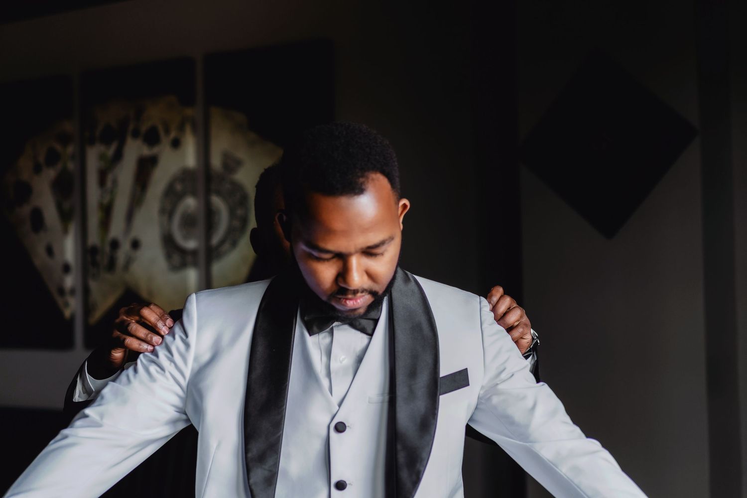 A person in a light gray suit jacket adjusts their attire while getting ready.