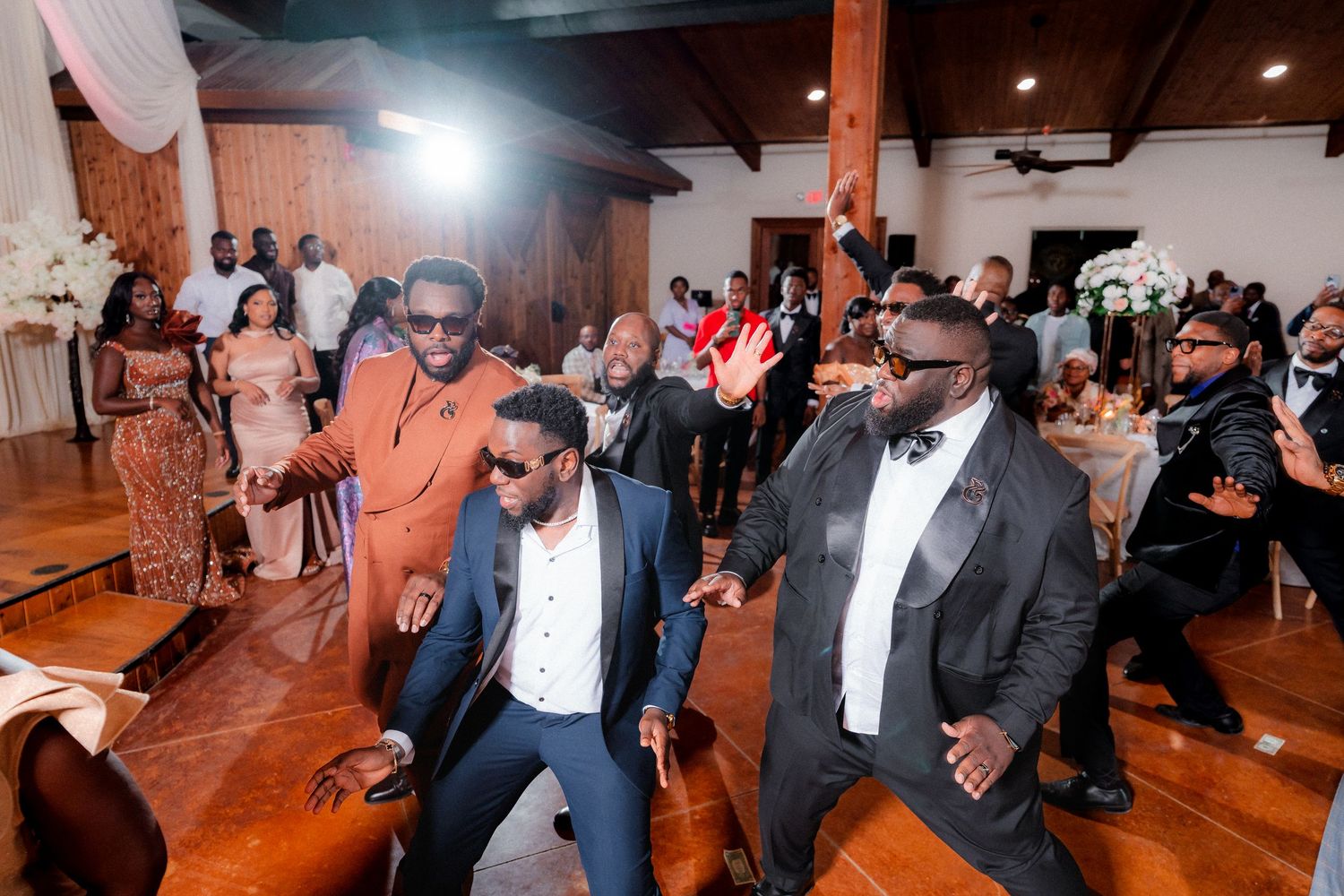 Wedding guests perform synchronized dance moves during reception celebration.