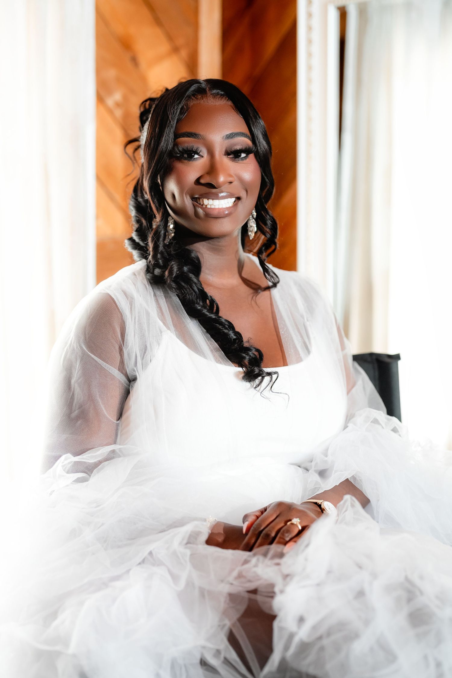 A bride in a flowing white wedding dress poses elegantly on a sofa in a series of romantic bridal portraits.