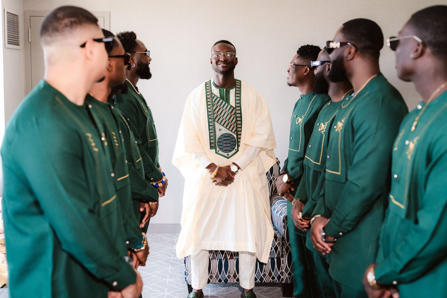 A group of groomsmen in matching green suits gather before the wedding ceremony.