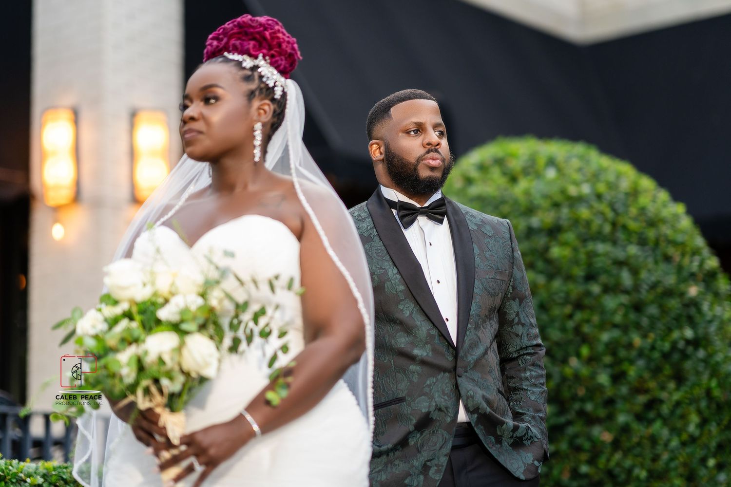 A bride and groom share a romantic moment together in formal wedding attire outdoors.