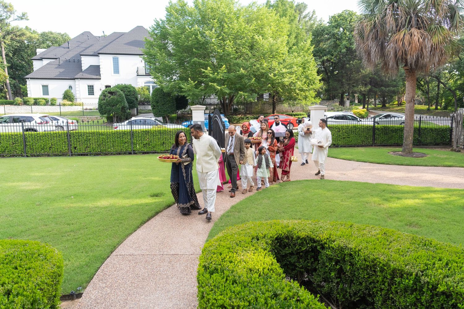 Wedding guests walk along landscaped pathways outside a Mediterranean-style venue.