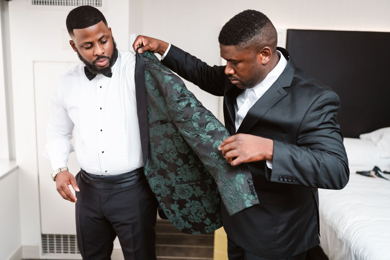 Final adjustments being made to formal wedding attire in a bright setting.