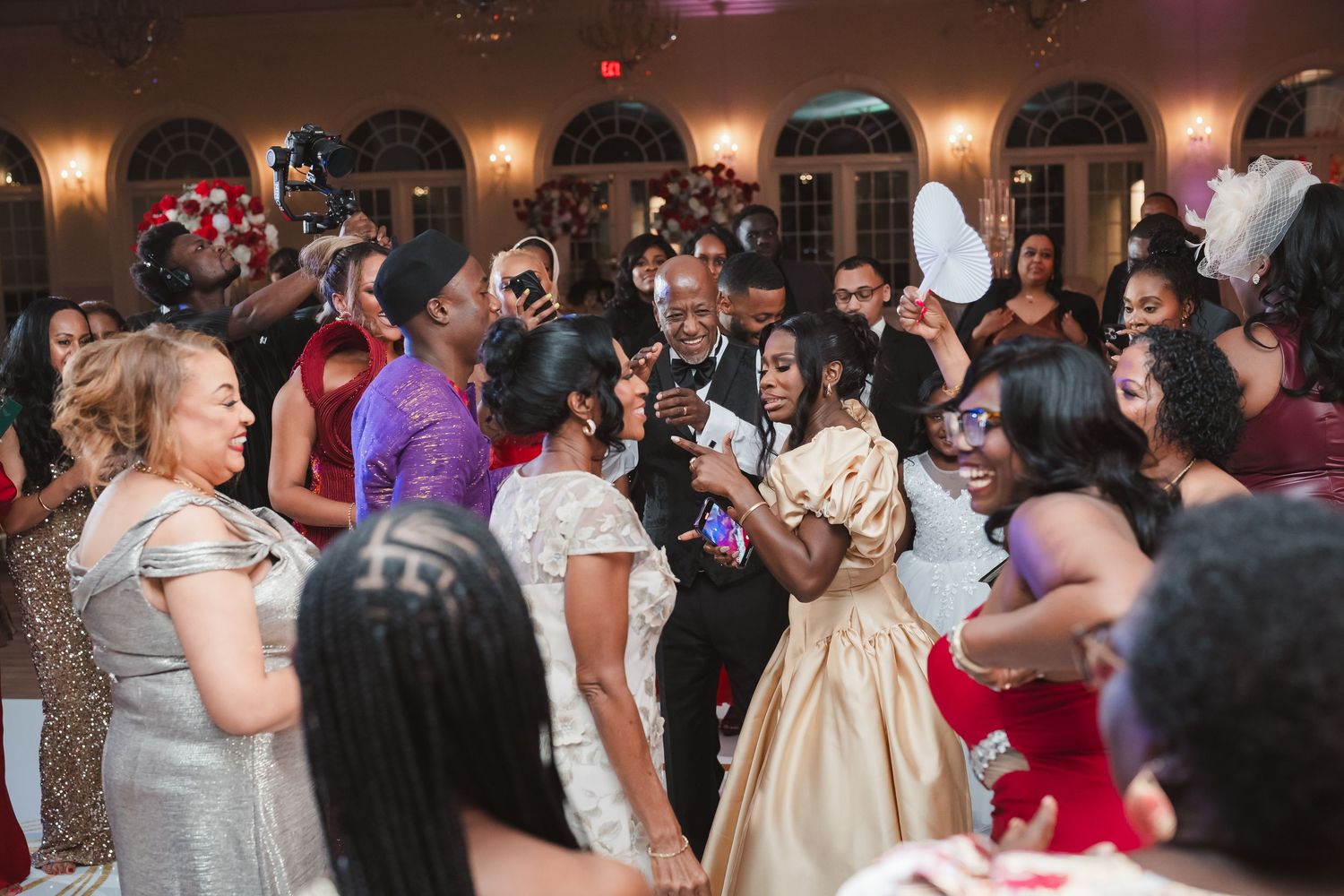 Wedding guests dancing and celebrating on a crowded dance floor at an evening reception.
