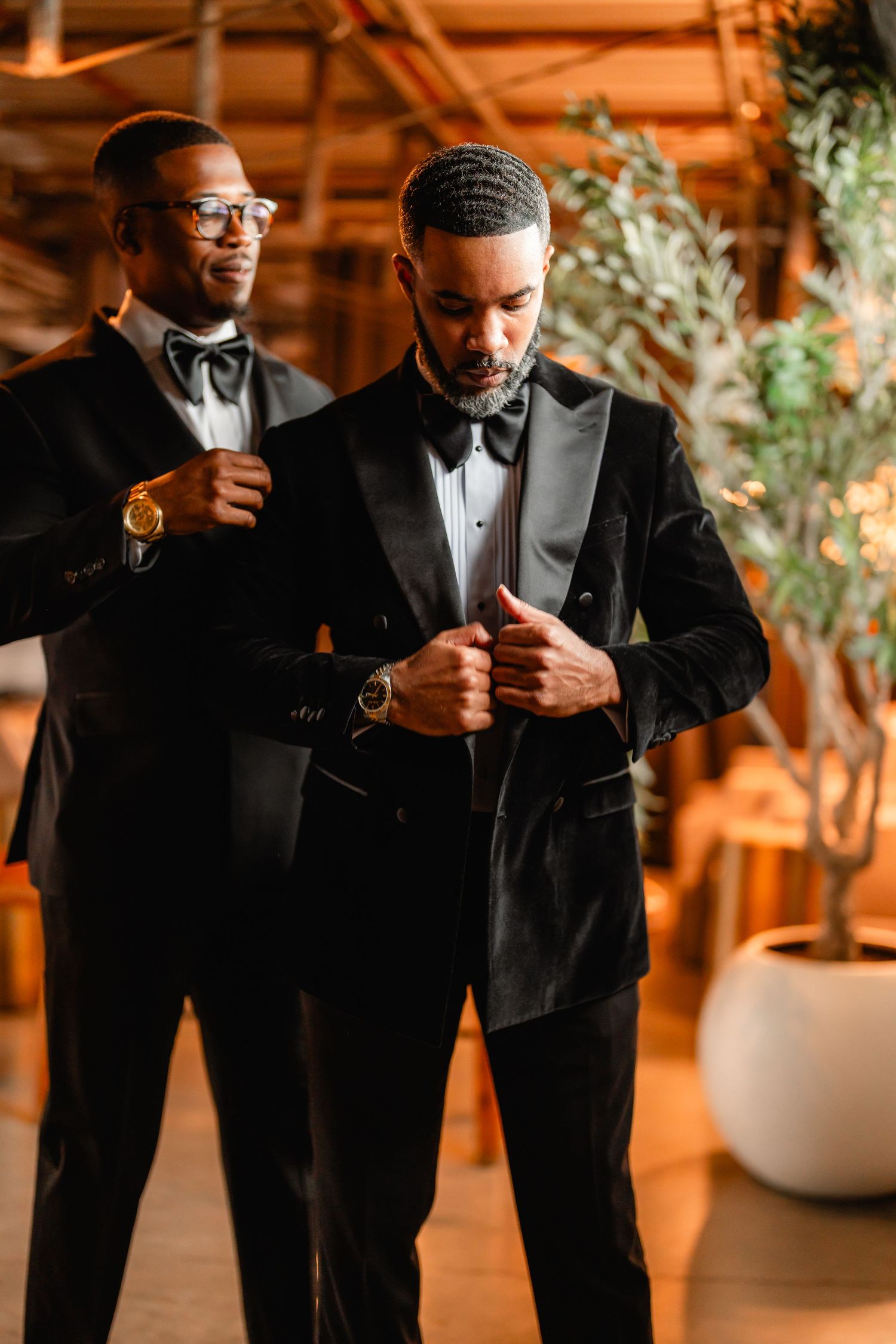 Groomsmen in black tuxedos share drinks and laughs during wedding celebration.