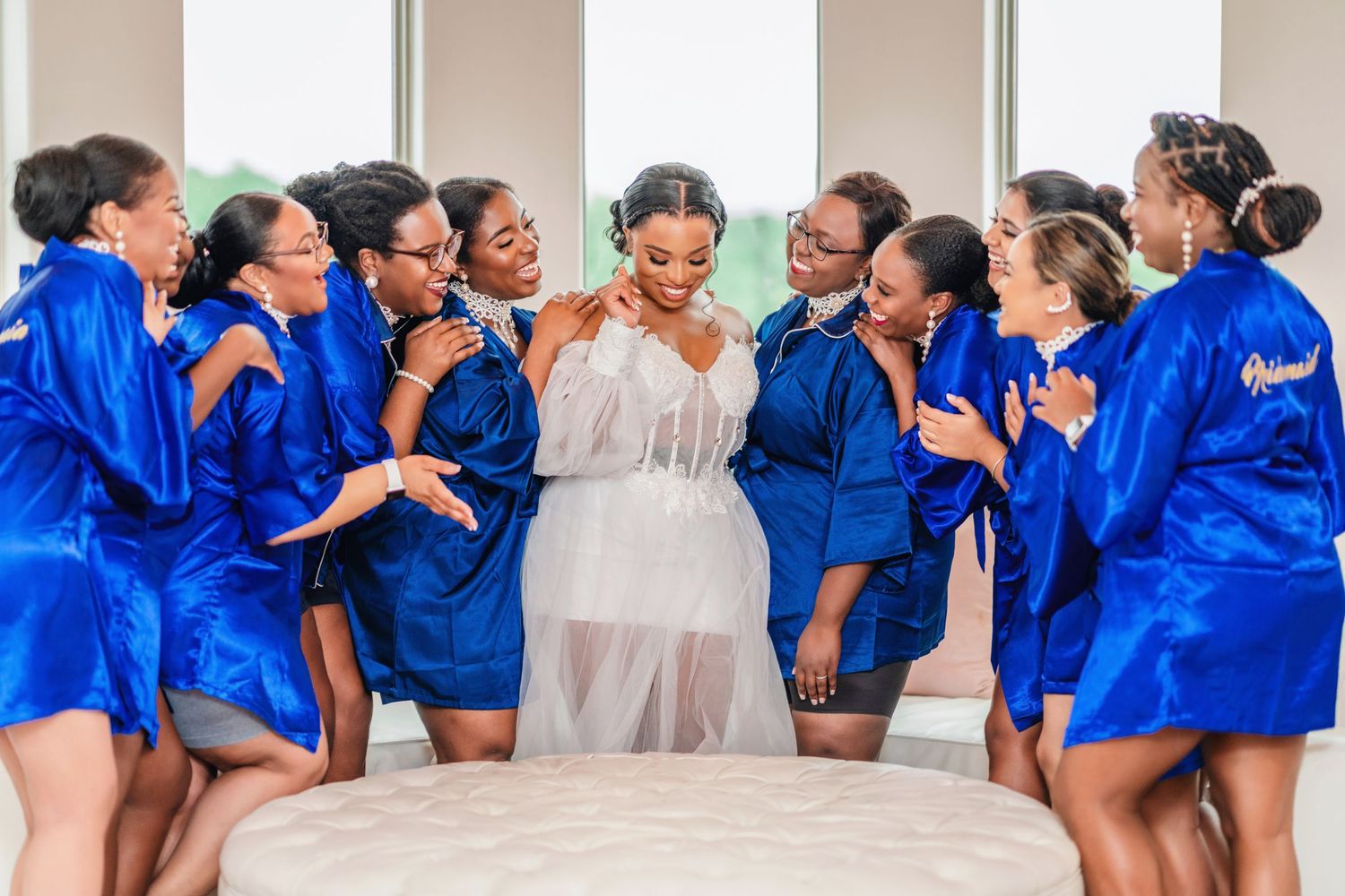 Wedding party in royal blue robes poses together in a bright indoor setting.