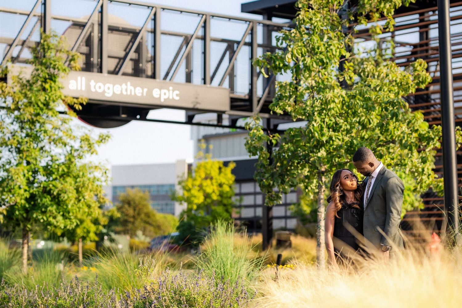 A wooden bridge walkway extends through natural vegetation with trees and buildings visible in the background.