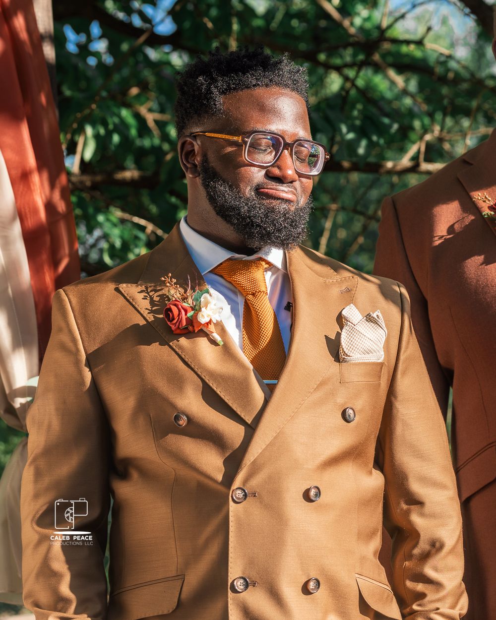 Groomsmen in tan suits posing together outdoors at a formal event.