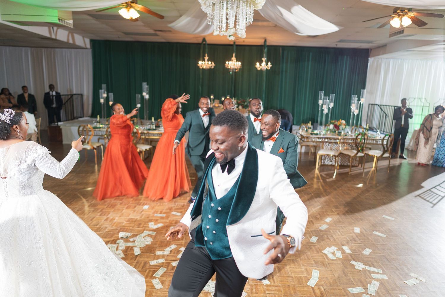 Spacious wedding reception hall with chandeliers and green drapery ready for celebration.