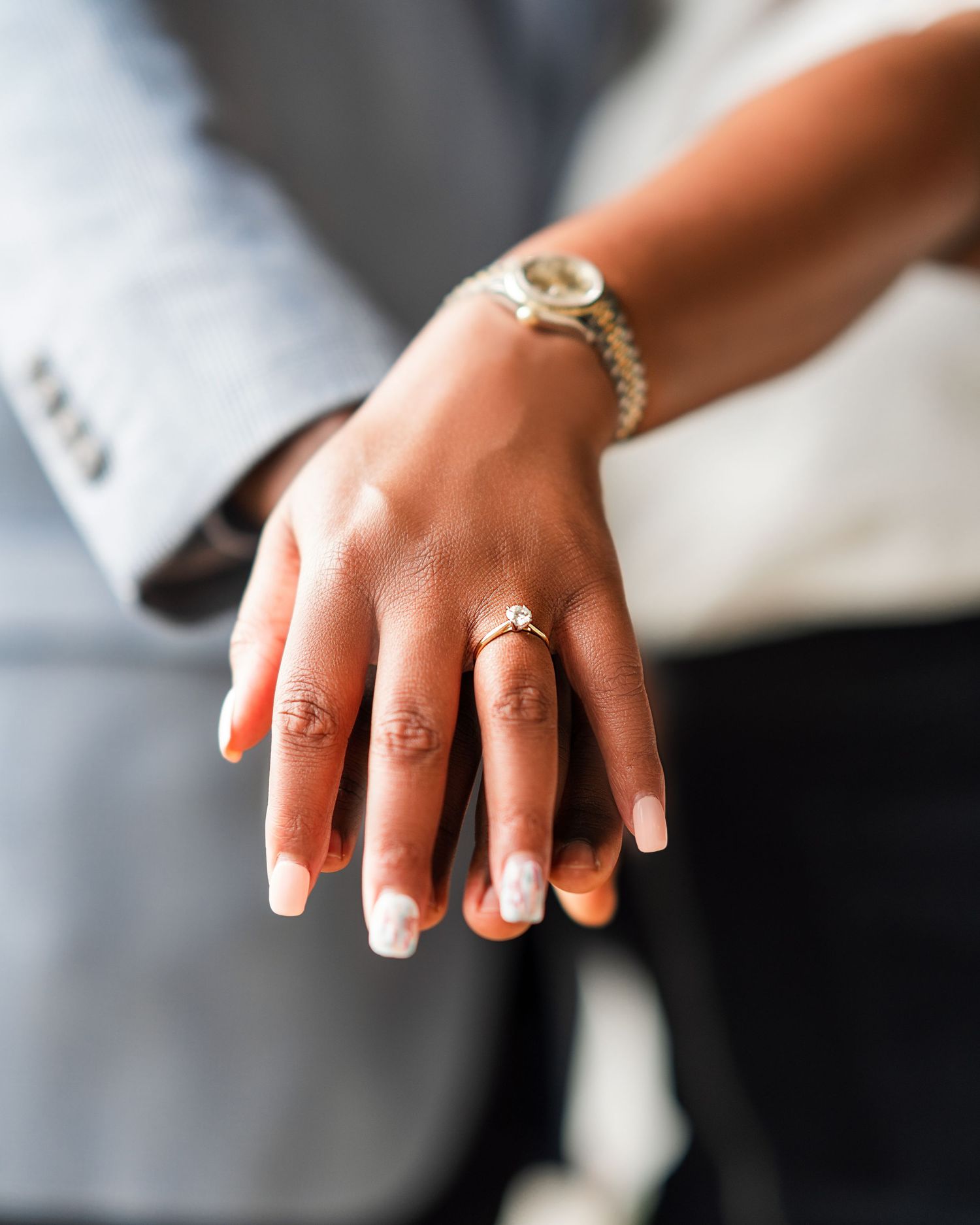 Close-up view of hands wearing engagement rings showing off wedding jewelry details in natural lighting.