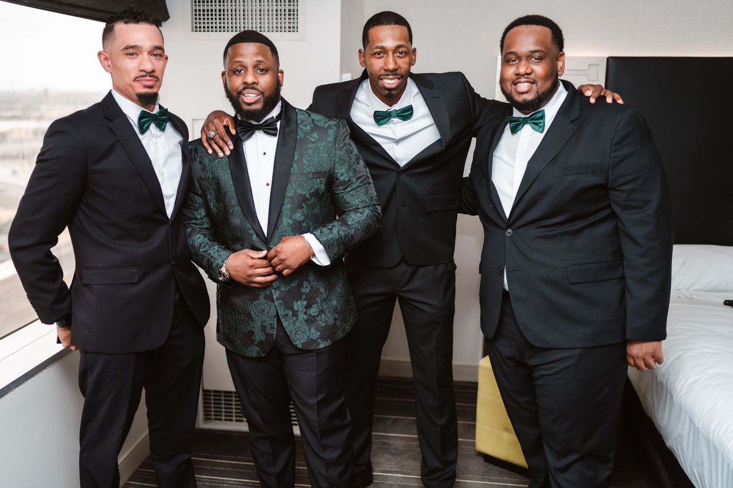 Groomsmen in black suits pose together during wedding celebration.
