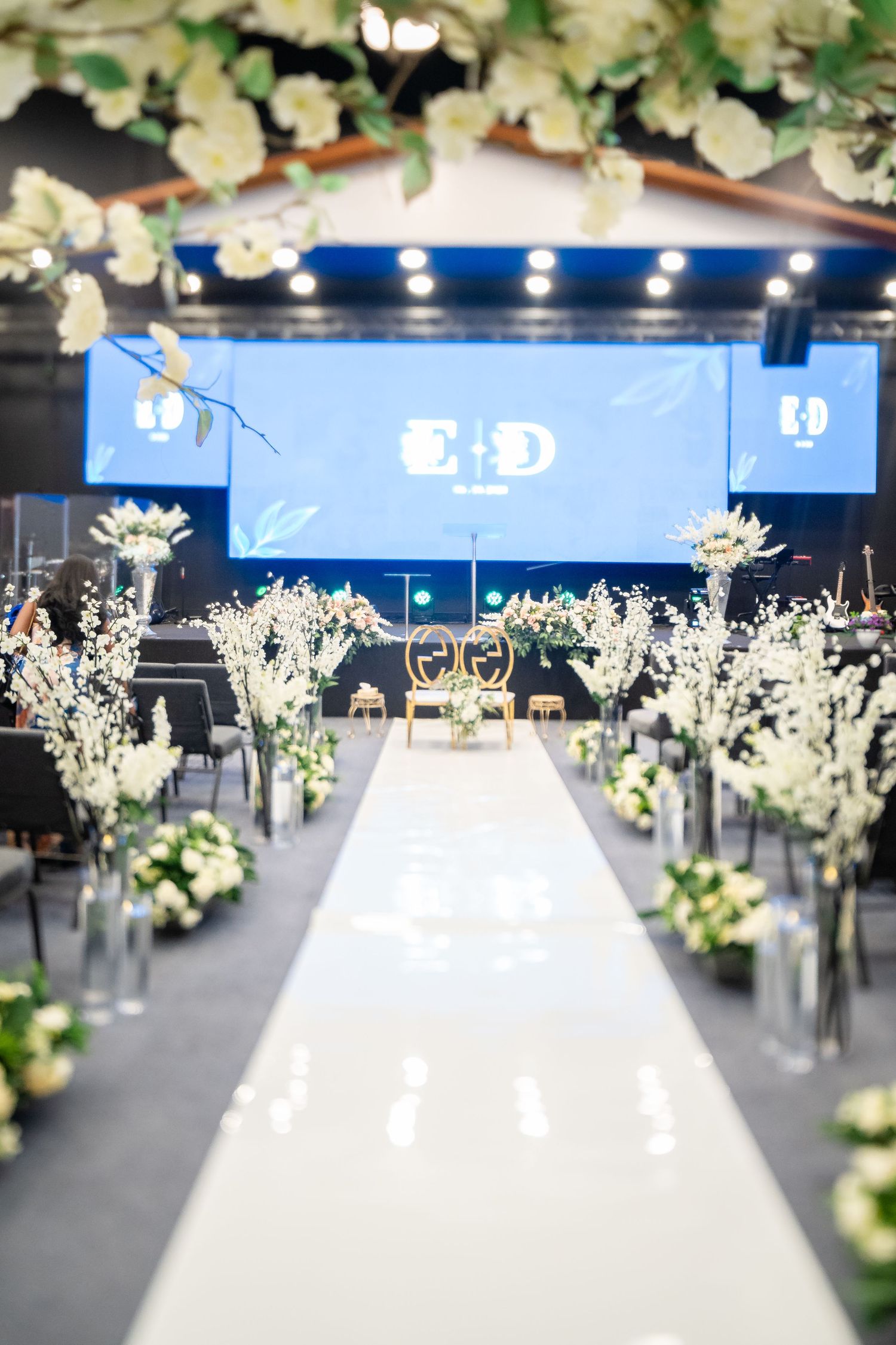 Elegant white floral arrangements with cascading orchids create a dramatic overhead display at an upscale event.